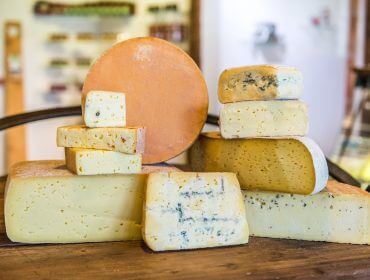 Blocchi e forme di cibo genuino impilati su un tavolo di legno in un ambiente rustico.