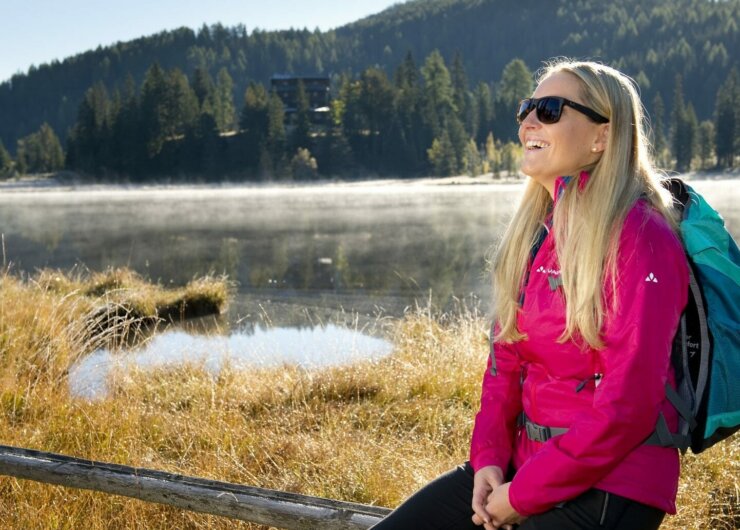 Relax al sole sul Prebersee nel Lungau Salisburghese Donna con occhiali da sole davanti al lago Prebersee, tra nebbia e luce solare d’alta quota