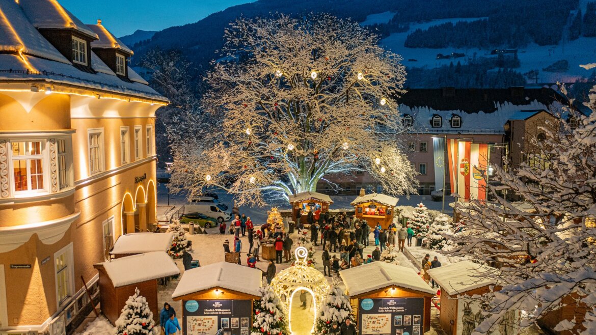 Mercatino di Natale a Bad Hofgastein con albero illuminato e visitatori tra la neve (Vista ingrandita)