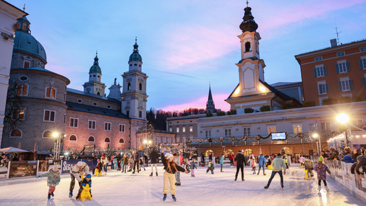 Pista di pattinaggio in Piazza Mozart con il Duomo di Salisburgo e la Chiesa di San Michele sullo sfondo (Vista ingrandita)