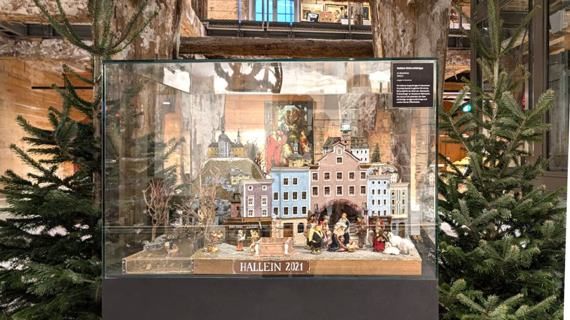 Esposizione nell’ex deposito del sale di Hallein, dove una vetrina mostra una suggestiva ricostruzione della città nel 2021, circondata da travi in legno storico © Weihnachtsmarkt Hallein Esposizione nell’ex deposito del sale di Hallein con una vetrina che mostra la città nel 2021 (Vista ingrandita)