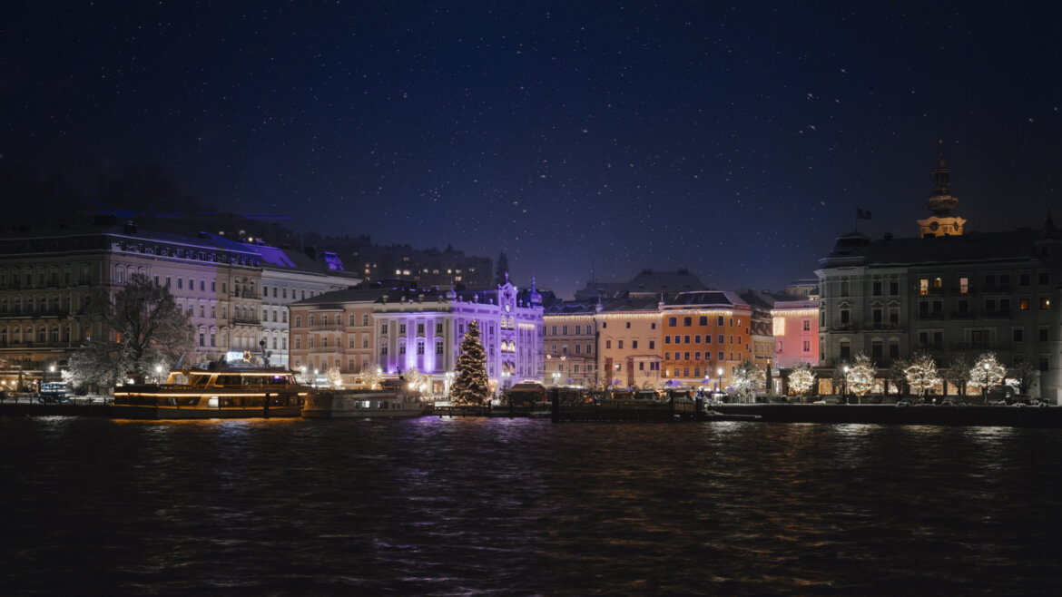 Gmunden illuminata dalle luci natalizie durante una nevicata vista dal lago Traunsee (Vista ingrandita)