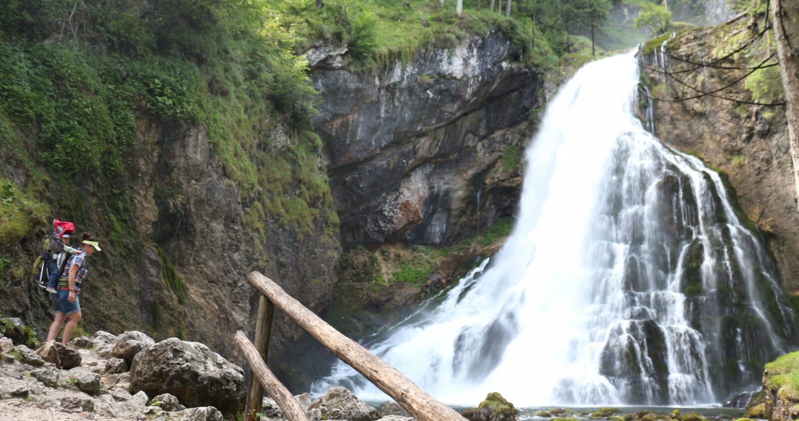 Cascata di Golling, Tennengau, Salisburghese Due escursionisti si trovano vicino a una ringhiera di legno e guardano una cascata circondata da rocce e vegetazione.