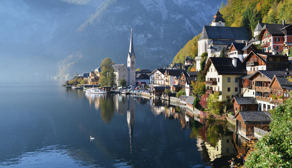 Veduta di Hallstatt, il villaggio più bello dell’Austria e famoso in tutto il mondo, con case colorate, due chiese e il riflesso delle montagne sul lago nella regione Dachstein Salzkammergut