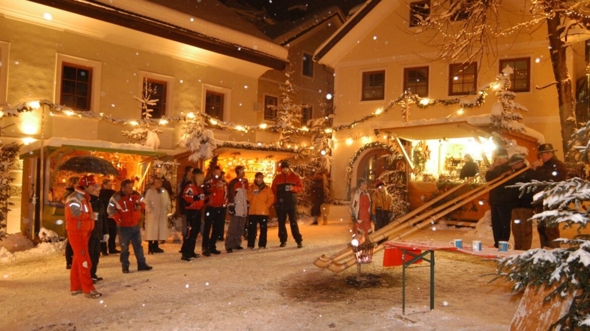 Gruppo di persone che ascolta tre suonatori di corno al mercatino d’Avvento di St. Michael nel Lungau (Vista ingrandita)