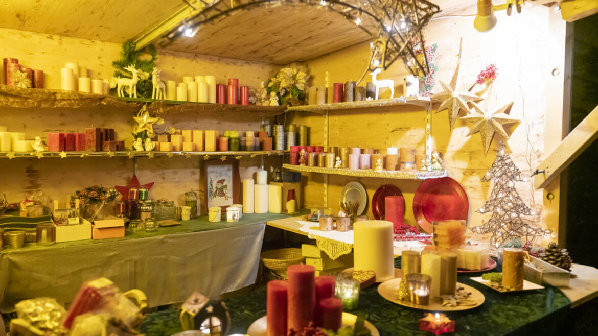 Bancarella con molte candele al mercatino d’Avvento nel Lungau che diffonde una luce calda e natalizia (Vista ingrandita)