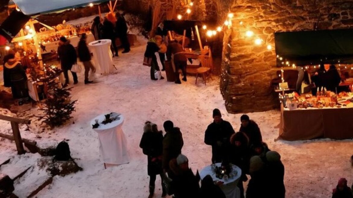 Vista dall’alto del cortile del Castello di Finstergrün con stand e luci calde che creano un’atmosfera intima (Vista ingrandita)