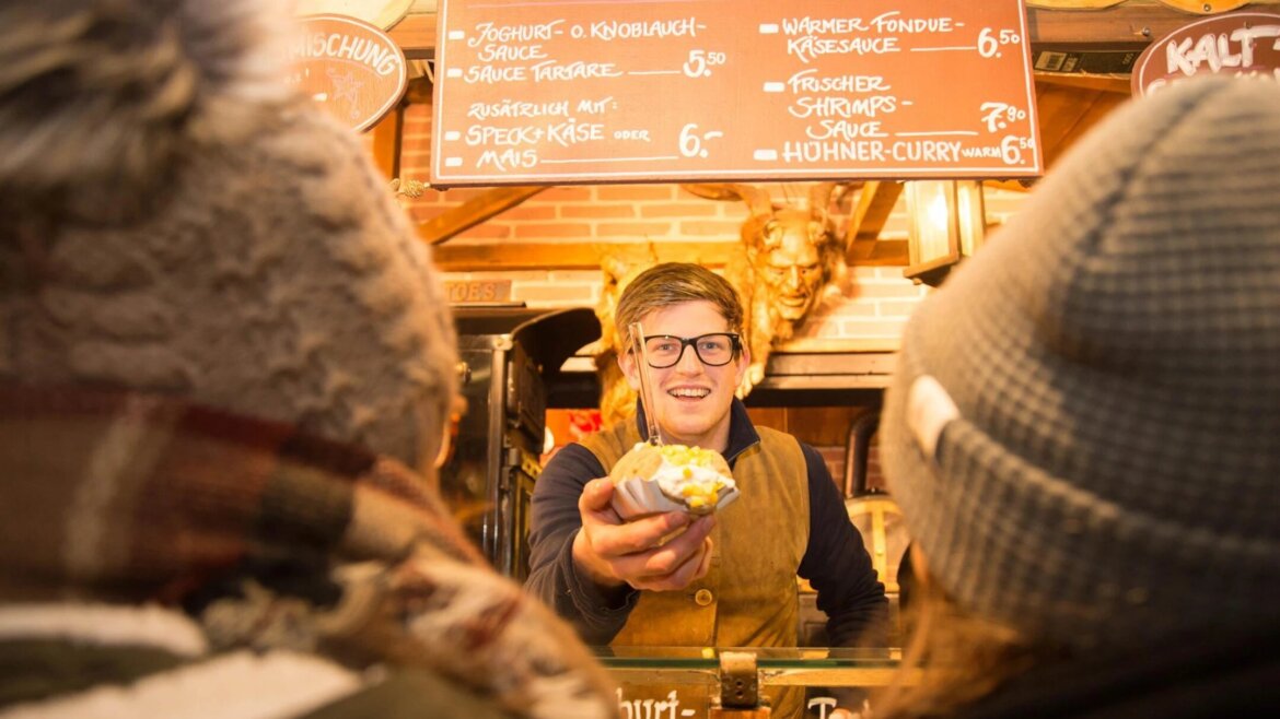 Venditrice che serve una patata al forno con panna acida al Mercato di Natale di Salisburgo (Vista ingrandita)