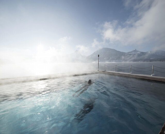 Piscina riscaldata dell’hotel Weisses Rössl a St. Wolfgang con vista sul lago Wolfgangsee e montagne innevate