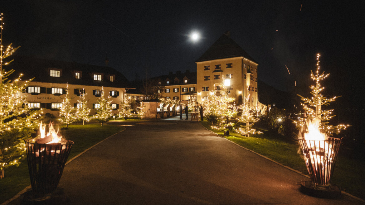 Cortile del 5* albergo Rosewood Schloss Fuschl con il mercatino dell’Avvento dei villaggi e alberi di Natale illuminati nella regione del lago Fuschlsee nel Salisburghese (Vista ingrandita)