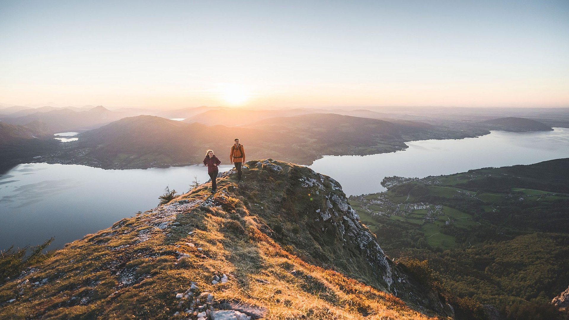 Coppia di escursionisti al tramonto su un crinale con vista sul lago Attersee nella regione Attersee-Attergau nel Salzkammergut.