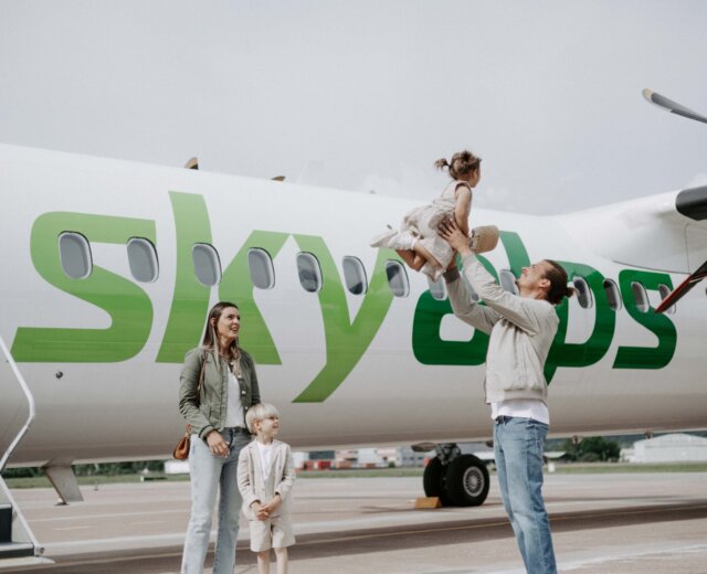 Prenotare il volo SkyAlps tra Roma e Salisburgo Famiglia accanto a un aereo SkyAlps prima della partenza