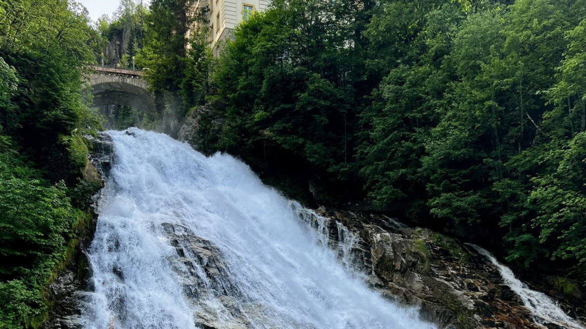 Poche località possono vantare una cascata così spettacolare proprio nel cuore del centro abitato: a Bad Gastein l’acqua è parte integrante del paesaggio urbano. © Azzurra Forti – BabyTrekking La cascata di Bad Gastein scorre tra le rocce sotto un ponte, circondata dalla vegetazione e dagli edifici nel cuore del paese. (Vista ingrandita)