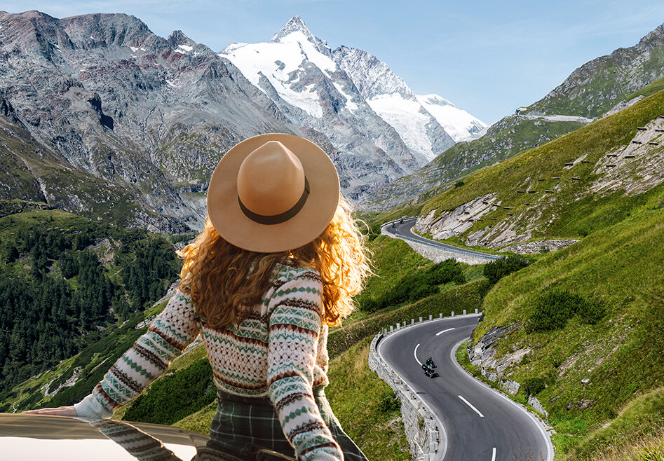 Vrouw met hoed zit op een auto en kijkt naar de Grossglockner Hochalpenstrasse en besneeuwde bergtoppen onder een heldere hemel. (Vergrote weergave)