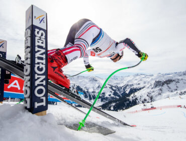 audi-fis-ski-weltcup-in-saalbach Een skiër in racepak duwt zich af van het starthek op een besneeuwde berghelling tijdens een skiwedstrijd.