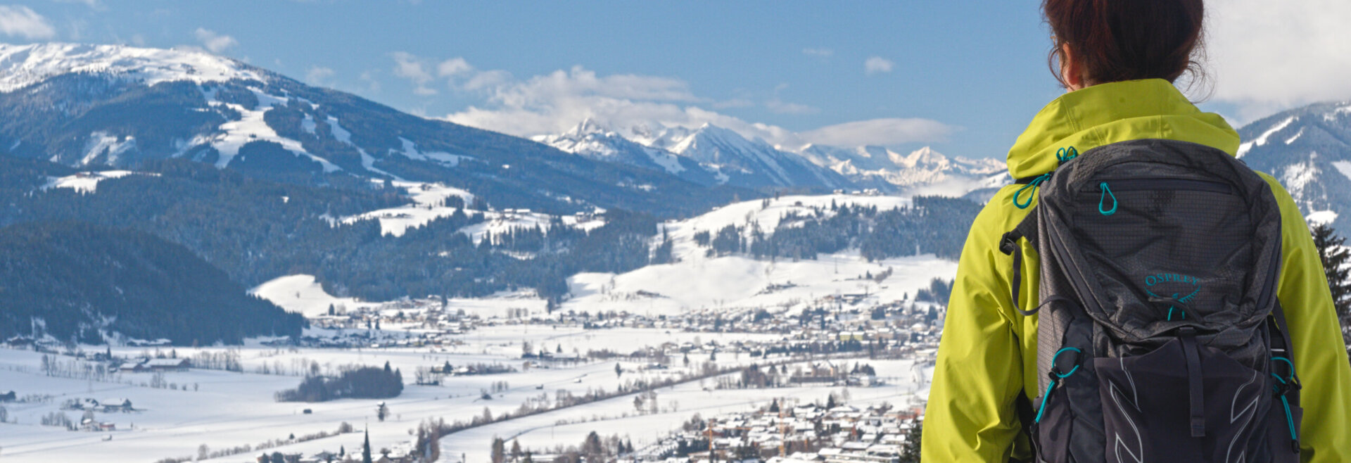 Een vrouw die aan het winterwandelen is, van achteren gezien, geniet van het uitzicht op het prachtige winterlandschap van Radstadt bij mooi weer.