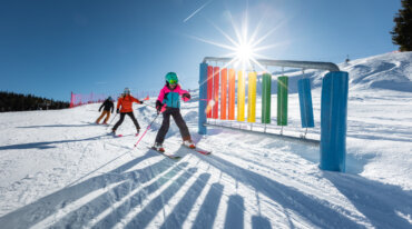 Kinderen hebben plezier tijdens het skiën in het Nationaal Park Hohe Tauern in het Raurisertal op de familieslope en genieten van de zon op de skipiste.