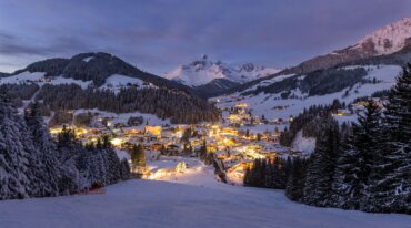 Foto van het met warm licht verlichte dal 's nachts, genomen vanaf de skipiste.