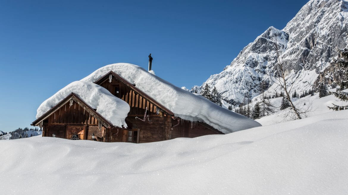 Górska chata na Ziemi Salzburskiej zakopana pod grubą kołderką śniegu, w otoczeniu białych górskich szczytów, to czysta zimowa romantyka 