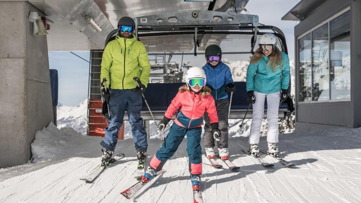 Salzburskie stacje narciarskie są idealnym miejscem na narty z całą rodzioną. Rodzice z dwójką dzieci na wyciągu krzesełkowym w Hochkönig.
