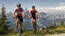 Dwóch kolarzy na rowerach górskich przmierza wysokogórskie ścieżki w imponującej scenerii salzburskich szczytów i grani..