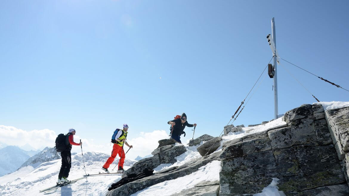 Skitouring- grupa narciarzy na nartach terenowych zdobywa górski szczyt.