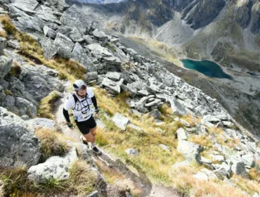 Osobisty szlak biegnący w górę skalistego zbocza górskiego w Adidas Infinite Trails, z jeziorem i klifami poniżej.