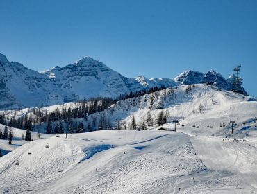 Pokryte śniegiem góry i stoki narciarskie w Salzburskim Saalachtal pod czystym, błękitnym niebem.