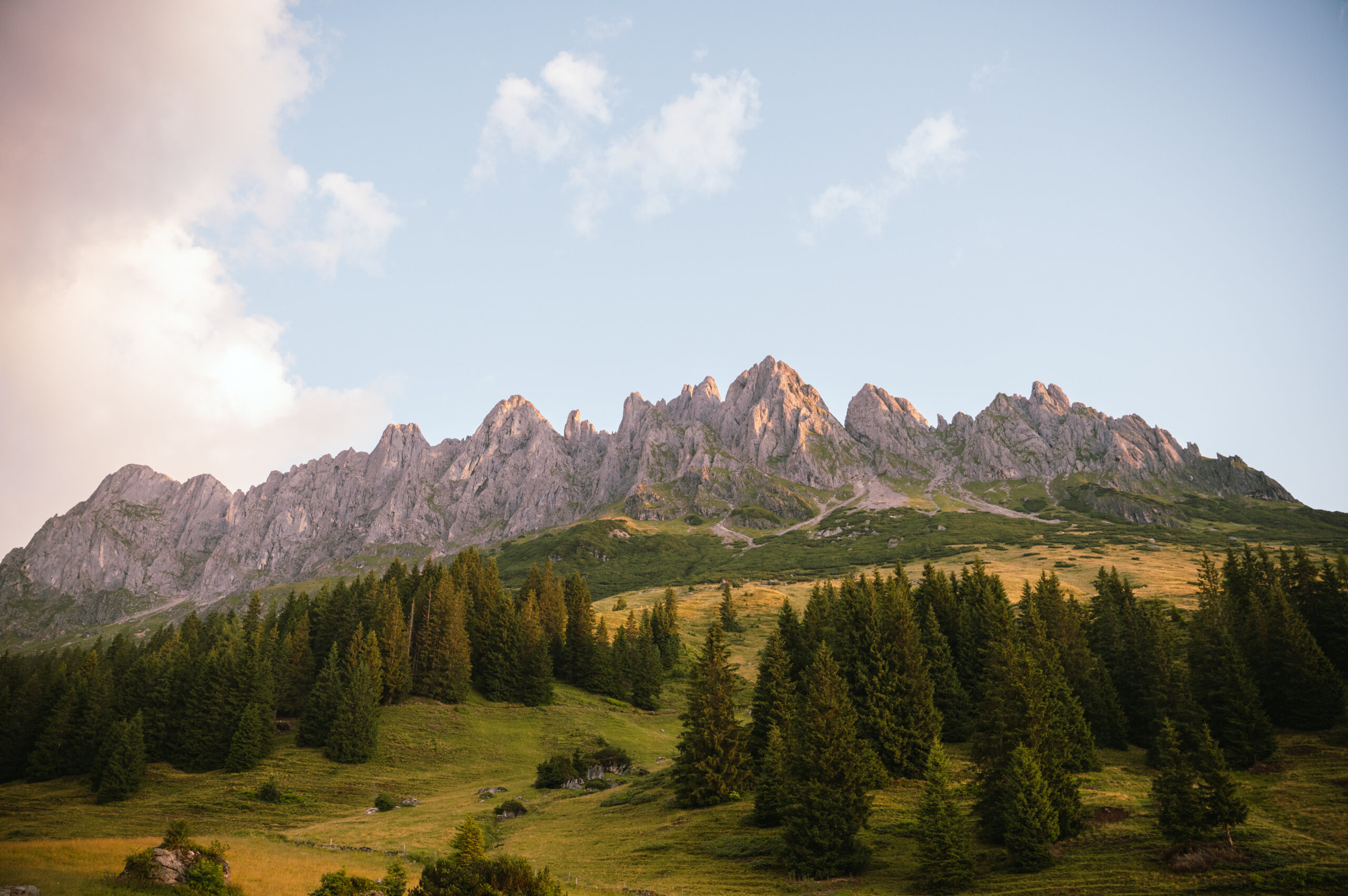 Poszarpane szczyty Hochkönig wznoszą się za wiecznie zielonymi lasami pod czystym niebem o wschodzie lub zachodzie słońca.