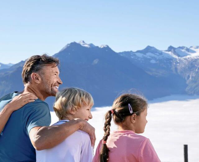 wandern_gipfelcferienregion_nationalpark_michael_huber_15_2-1920×658 Uśmiechnięta rodzina cieszy się słonecznym dniem ponad chmurami w Wypoczynkowym Parku Narodowym Wysokie Taury.