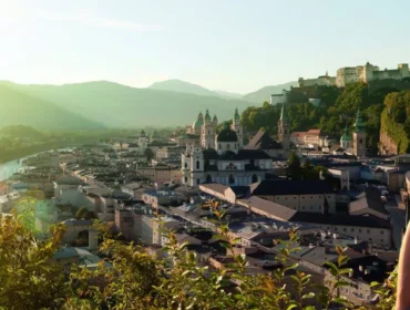 Para obejmuje się, podziwiając malowniczy krajobraz Salzburga o zachodzie słońca, z górami w tle.