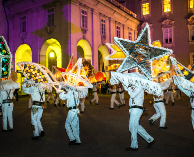 Ludzie w białych strojach niosą gwiezdne latarnie podczas najważniejszych nocnych imprez na Ziemi Salzburskiej.