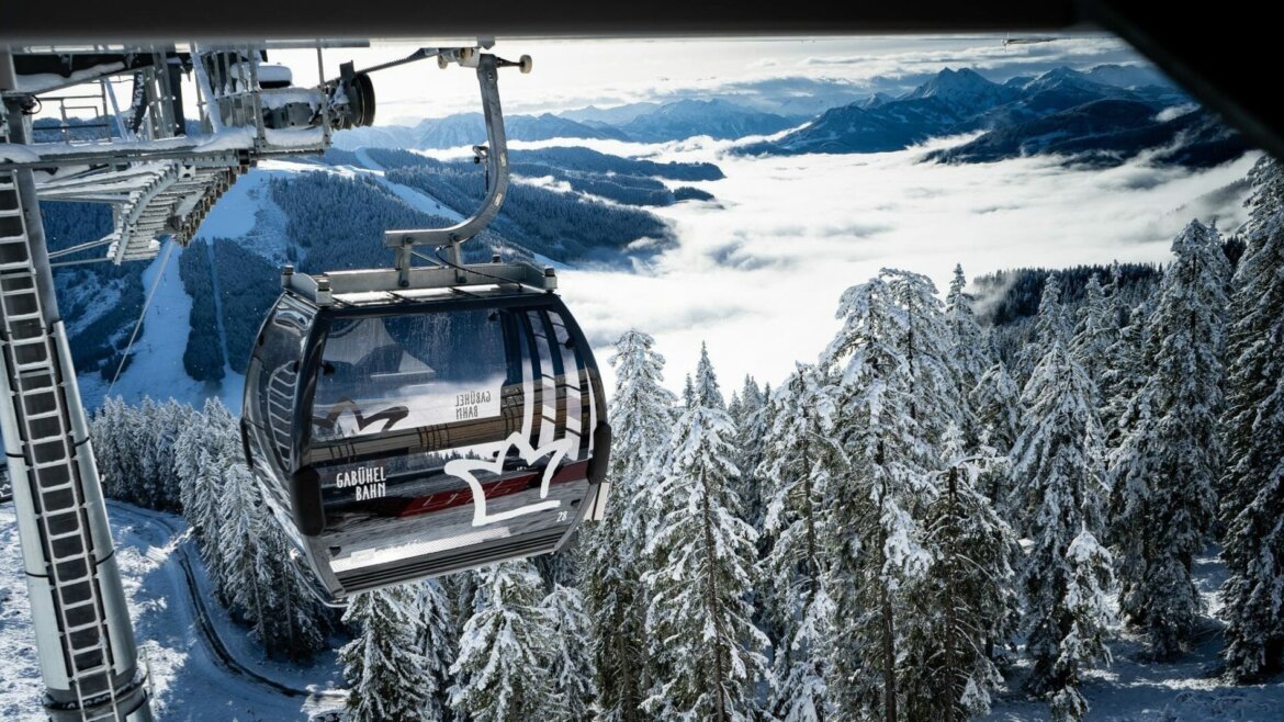 Kolejka gondolowa Gabühelbahn w Dienten © Hochkönig Tourismus Kolejka gondolowa nad ośnieżonymi drzewami i górami z chmurami w tle podczas Zima w Hochkönig. (Powiększony widok)