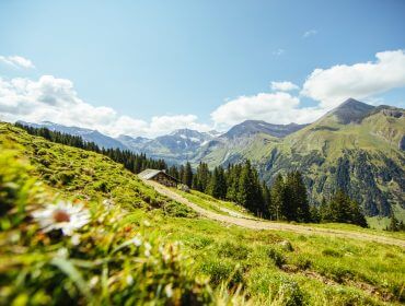 Malowniczy górski krajobraz z zielonymi wzgórzami i domkiem, uchwycenie radości oczekiwania pod błękitnym niebem.