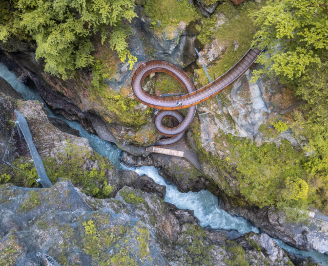 Widok z lotu ptaka na krętą drewnianą kładkę Skalny wąwóz Liechtensteinklamm nad bujnym, skalistym wąwozem rzeki.