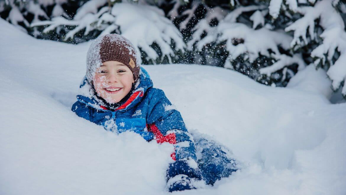 Zima na Ziemi Salzburskiej budzi w każdym z nas wspomnienia szczęśliwego dzieciństwa. Na zdjęciu chłopiec w sapie śniegu.