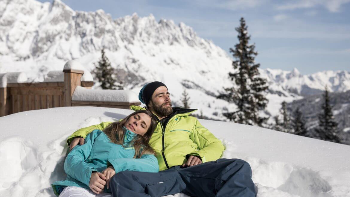 Para narciarzy odpoczywa w śnieżnej zaspie. Śnieg i słońce to magiczna mikstura, która wycisza i uspokaja, koi ducha i wyzwala hormony szczęścia.