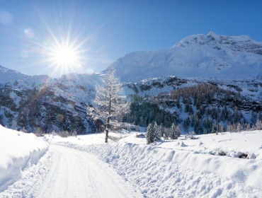 Raurisertal Winter Talschluss Kolm Saigurn4(c)TVB Rauris Fotograf Lukas Pilz Słońce świeci nad zaśnieżonym krajobrazem Raurisertal - idealnym na urlop zimowy blisko natury.