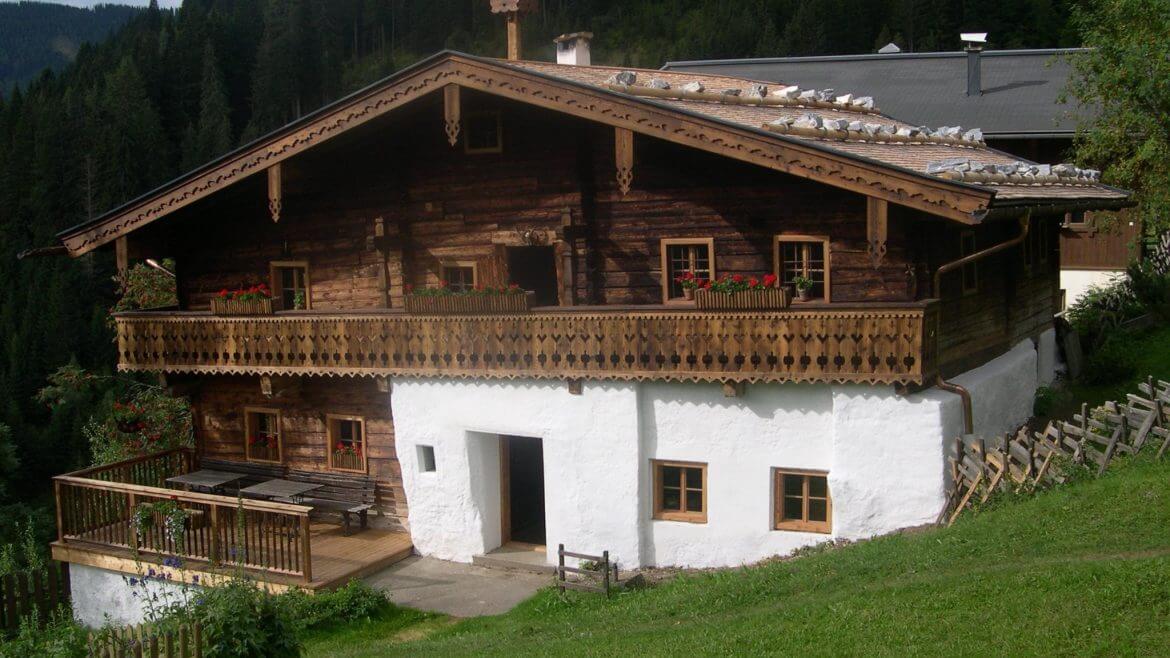 Zabytkowy drewniany dom na wysokiej podmurówce, z drewnianym dachem obciążonym kamieniami. Część starego gospodarstwa alpejskiego. Skansen w Grünegg.