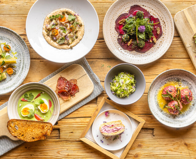 Różnorodne dania dla smakoszy, idealne na turystkę zielarską, ułożone na rustykalnym drewnianym stole.