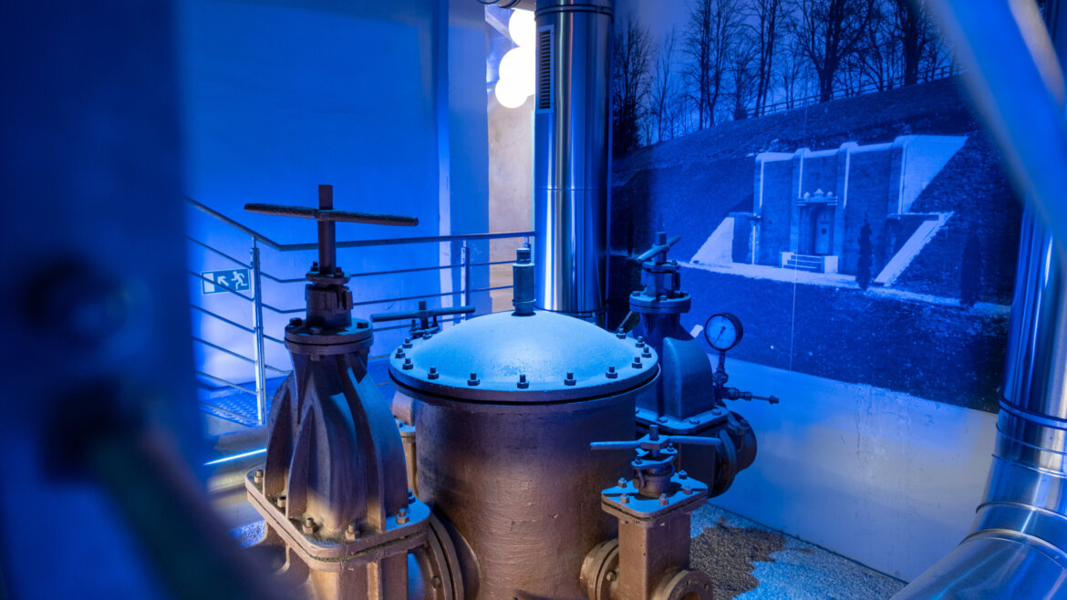 Duże przemysłowe zawory i rury w WasserSpiegel, z muralem w tym podświetlonym na niebiesko pomieszczeniu muzeum hydrotechniki. (Powiększony widok)