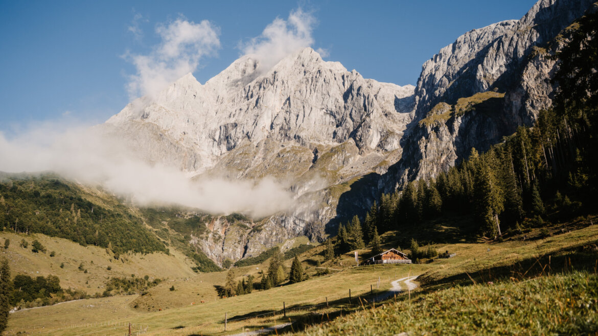 Kręta ścieżka turystyka piesza w regionie Hochönig prowadzi do domku wśród skalistych gór i zielonych wzgórz. (Powiększony widok)