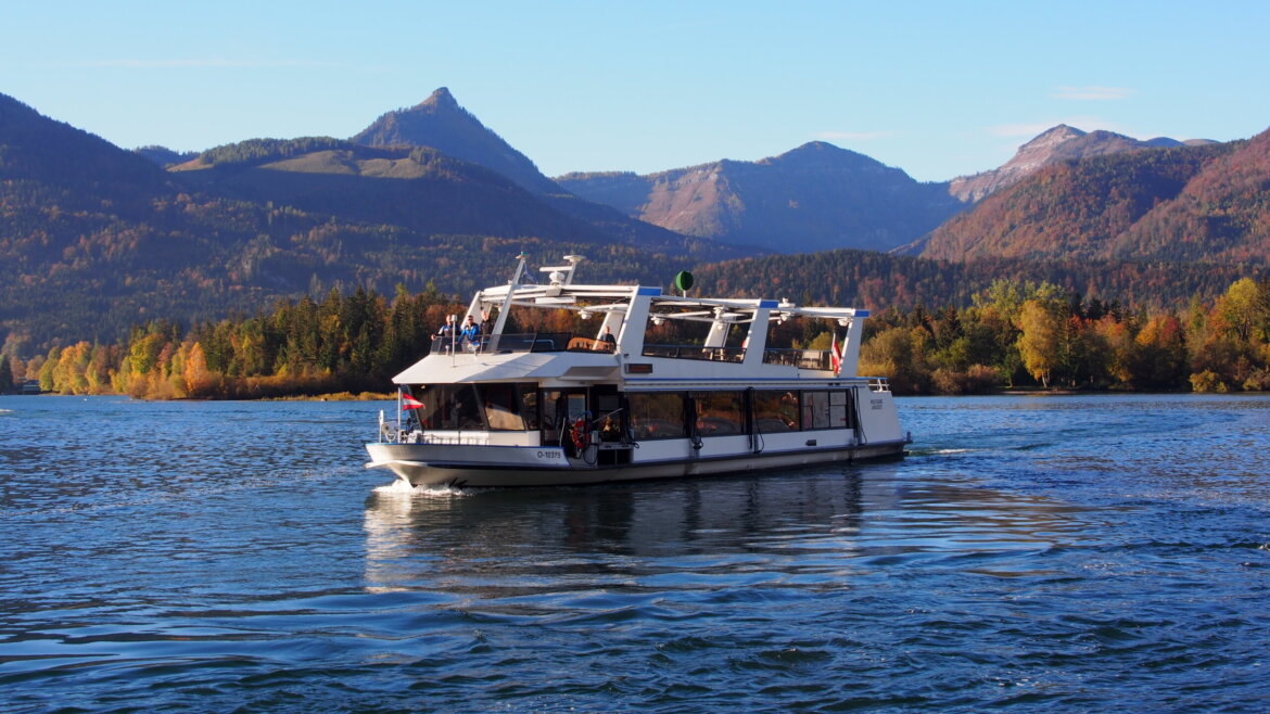 Statek białej floty WolfgangseeSchiffahrt© Salzburg AG Tourismus GmbH Biała łódź na jeziorze Wolfgangsee z pasażerami, statkiem w Salzkammergut, otoczona zalesionymi wzgórzami i górami. (Powiększony widok)