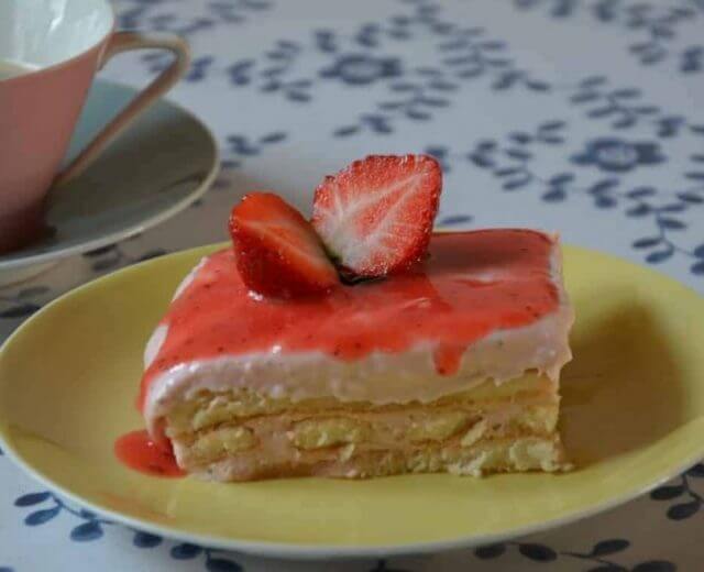 Letnia wariacja klasycznego włoskiego deseru tiramisu polane sosem truskawkowym. i ozdobione połówkami owoców.