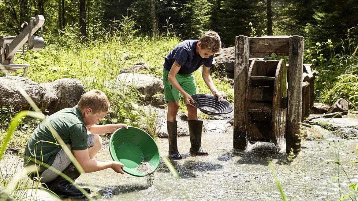 Wakacje z rodziną nad złotonośnym potokiem. Dwóch chłopców wypłukuje złoto w potoku w Bodenhaus.