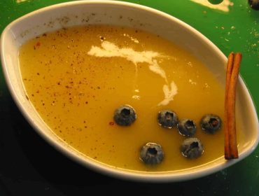 Zupa krem z jabłek na zimno, podana w ceramicznej miseczce w kształcie łódeczki, przybrana grubo zmielonym kolorowym pieprzem, owocami jagód i laską cynamonu.
