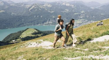 Rodzina z dwójką dzieci podchodzą pieszo ze stacji górnej kolejki na szczyt góry Schafberg.