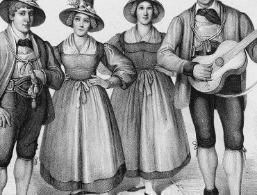 Cztery osoby w tradycyjnych strojach, pokazujące kulturowe rozpowszechnienie - jeden mężczyzna uśmiecha się, trzymając gitarę.