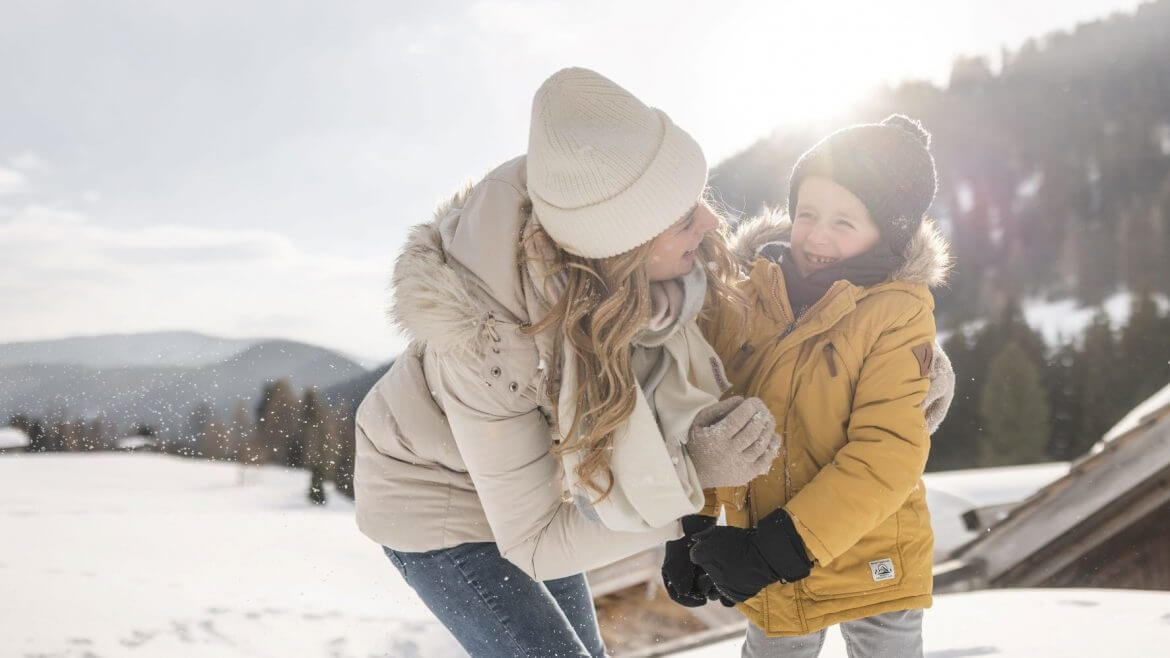 Mama z synem na śniegu. Na Ziemi Salzburskiej rodzice wkładają dzieciom miłość do zimy do kolebki.