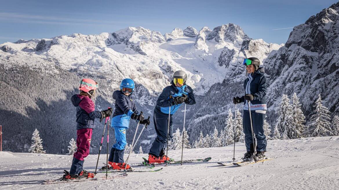 Rodzina z dwójką dzieci na nartach w Dachstein West. W tle widoczny lodowiec Dachstein